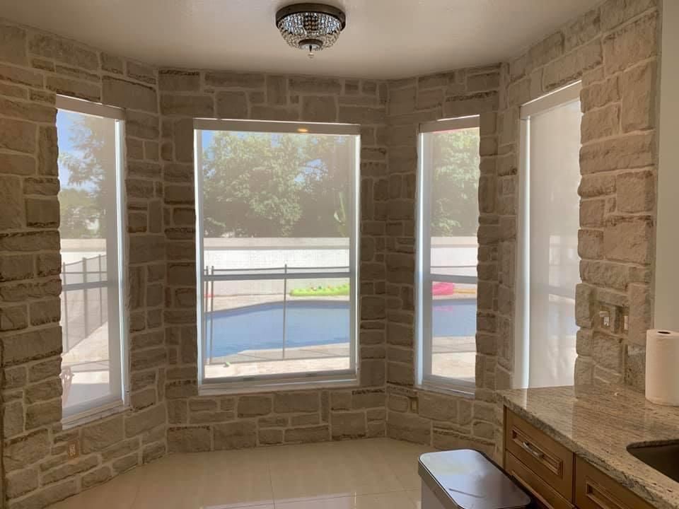 An empty room with a brick wall and a swimming pool in the background.
