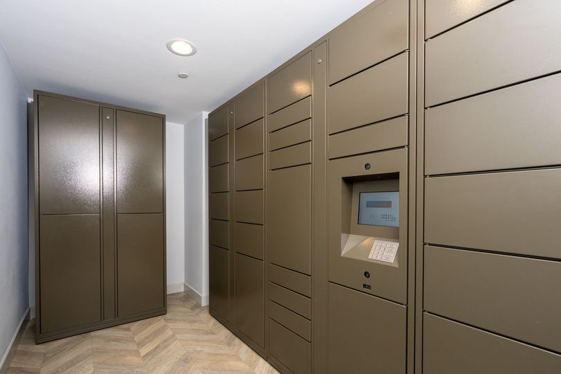 Modern apartment hallway with brown mail lockers and a wall-mounted parcel locker kiosk