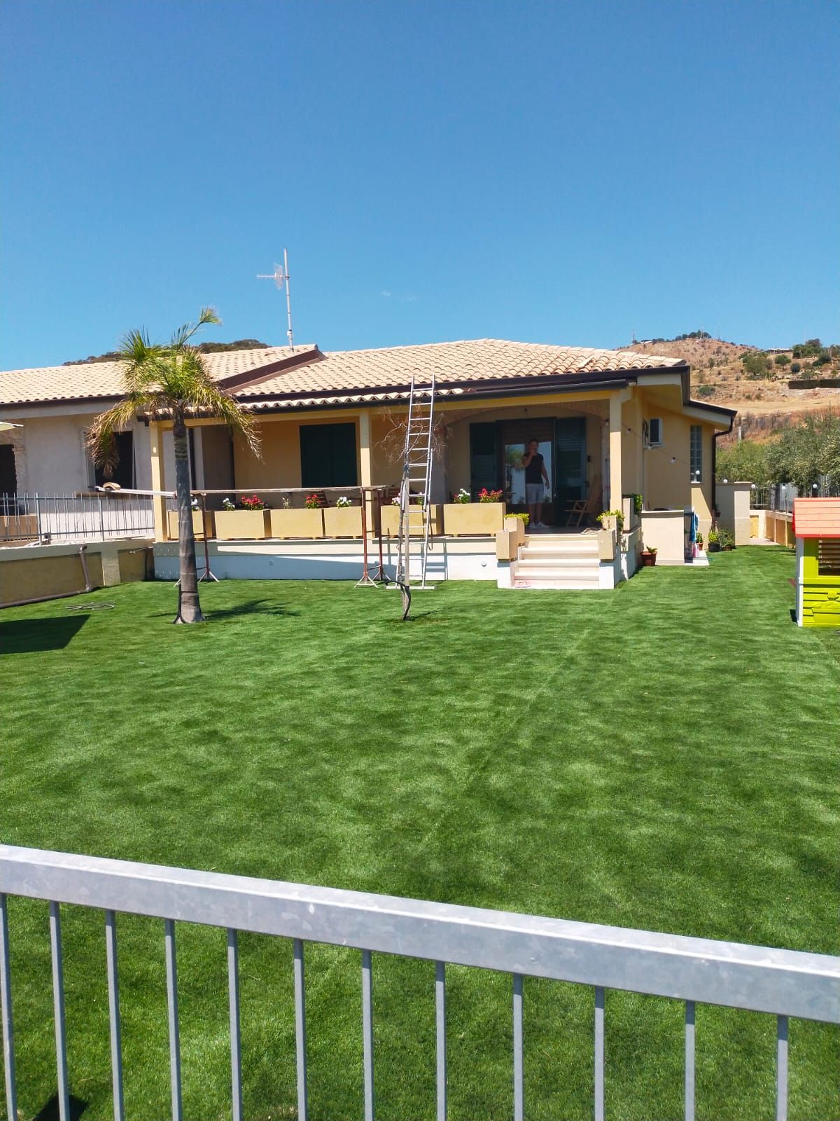 Una grande casa con davanti un rigoglioso prato verde.