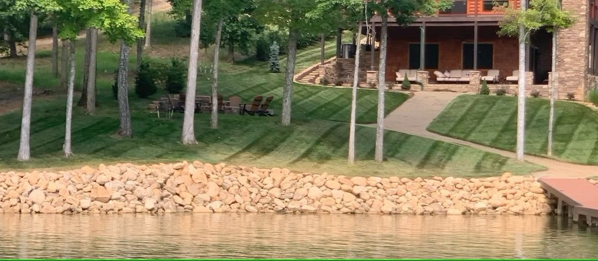 A house is sitting next to a lake with a dock in front of it.