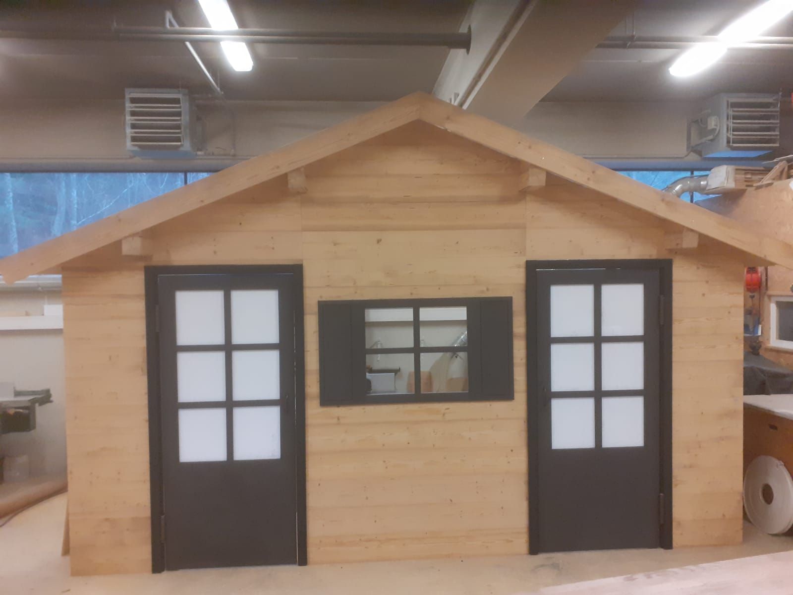 Ein kleines Holzhaus mit schwarzen Türen und Fenstern