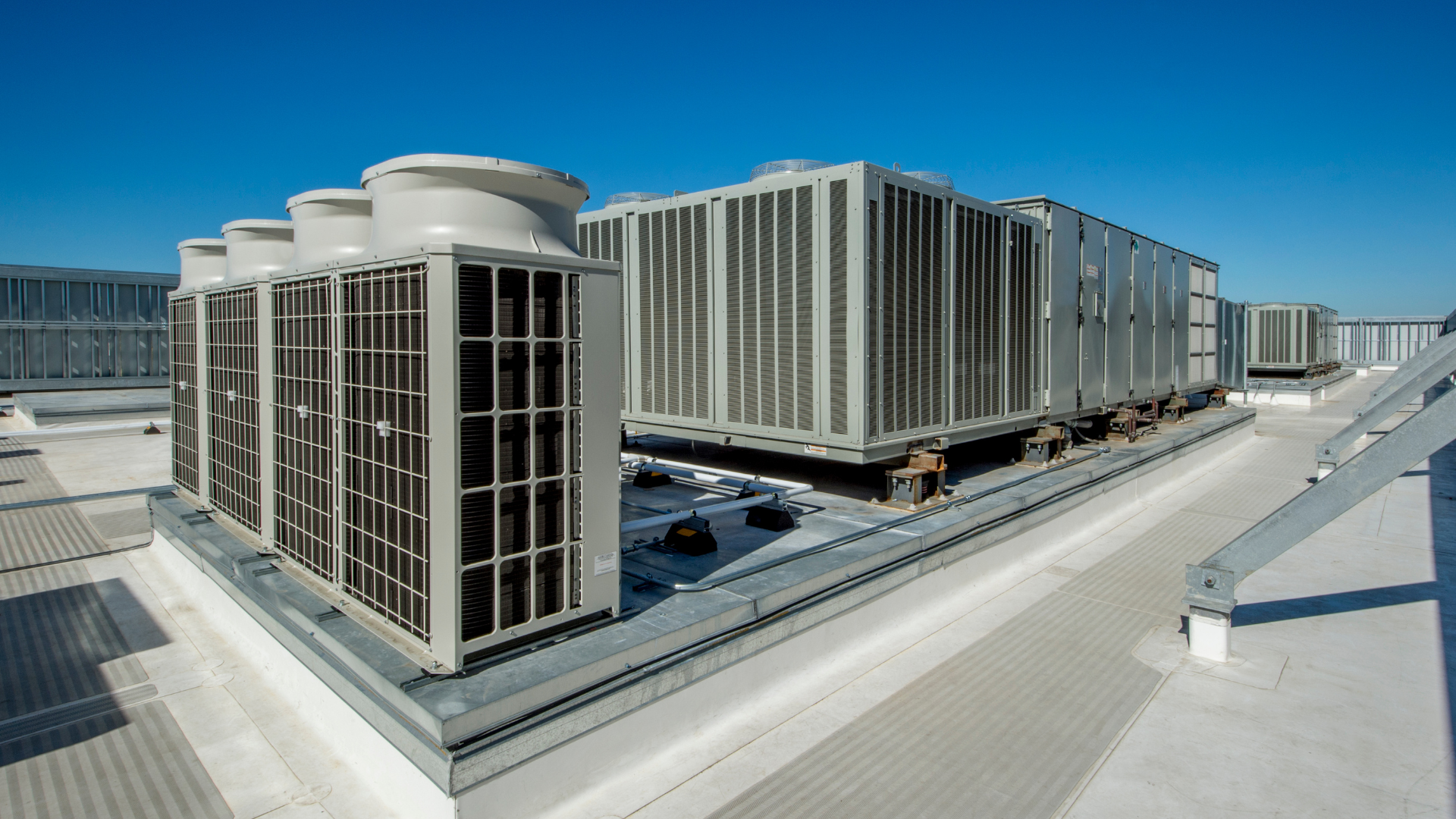There are a lot of air conditioners on the roof of a building.
