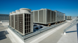 There are a lot of air conditioners on the roof of a building.