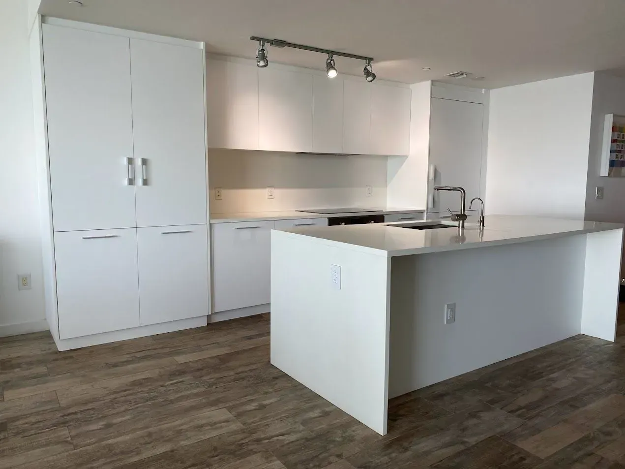A kitchen with white cabinets and a large island in the middle.
