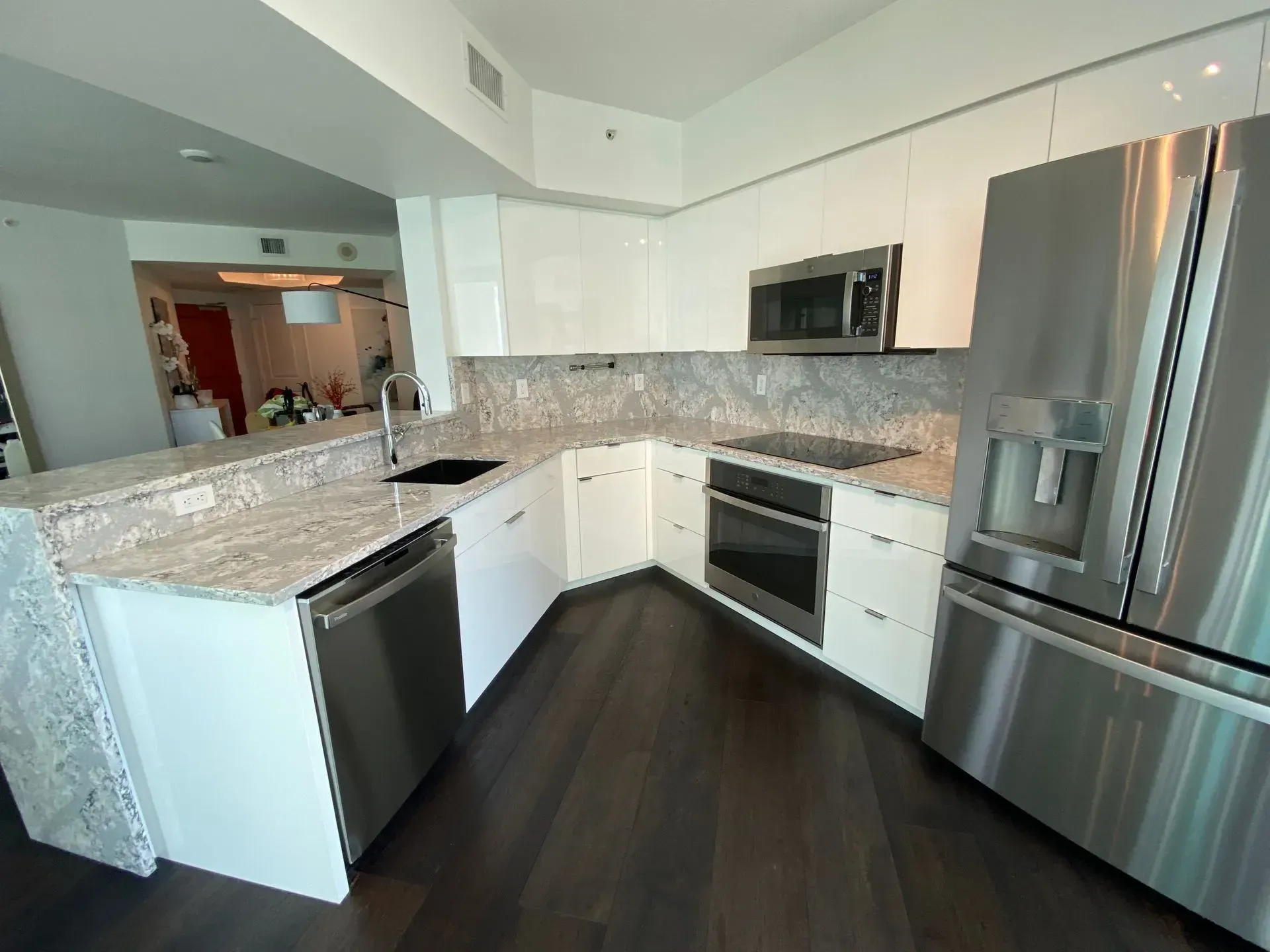 AWhite Kitchen with Quarzt countertop and dark wood flooring.
Here in Fort Lauderdale, FL