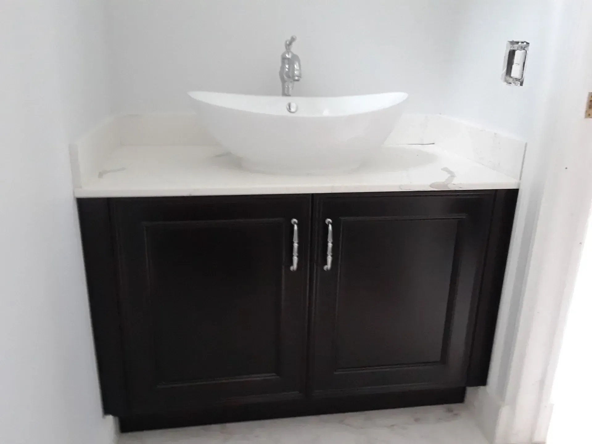 A bathroom with black cabinets and a white sink