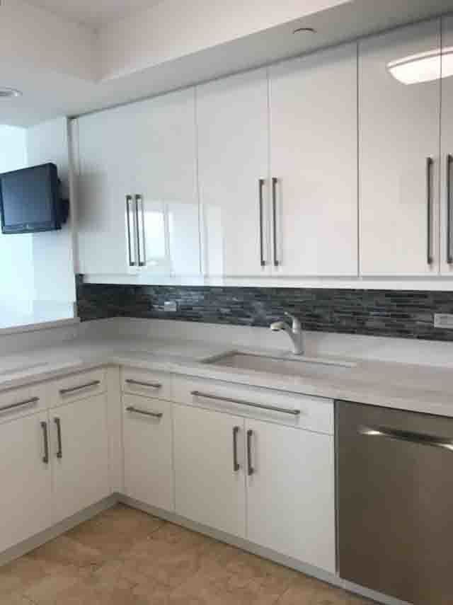 A kitchen with white cabinets , a sink , and a stainless steel dishwasher.