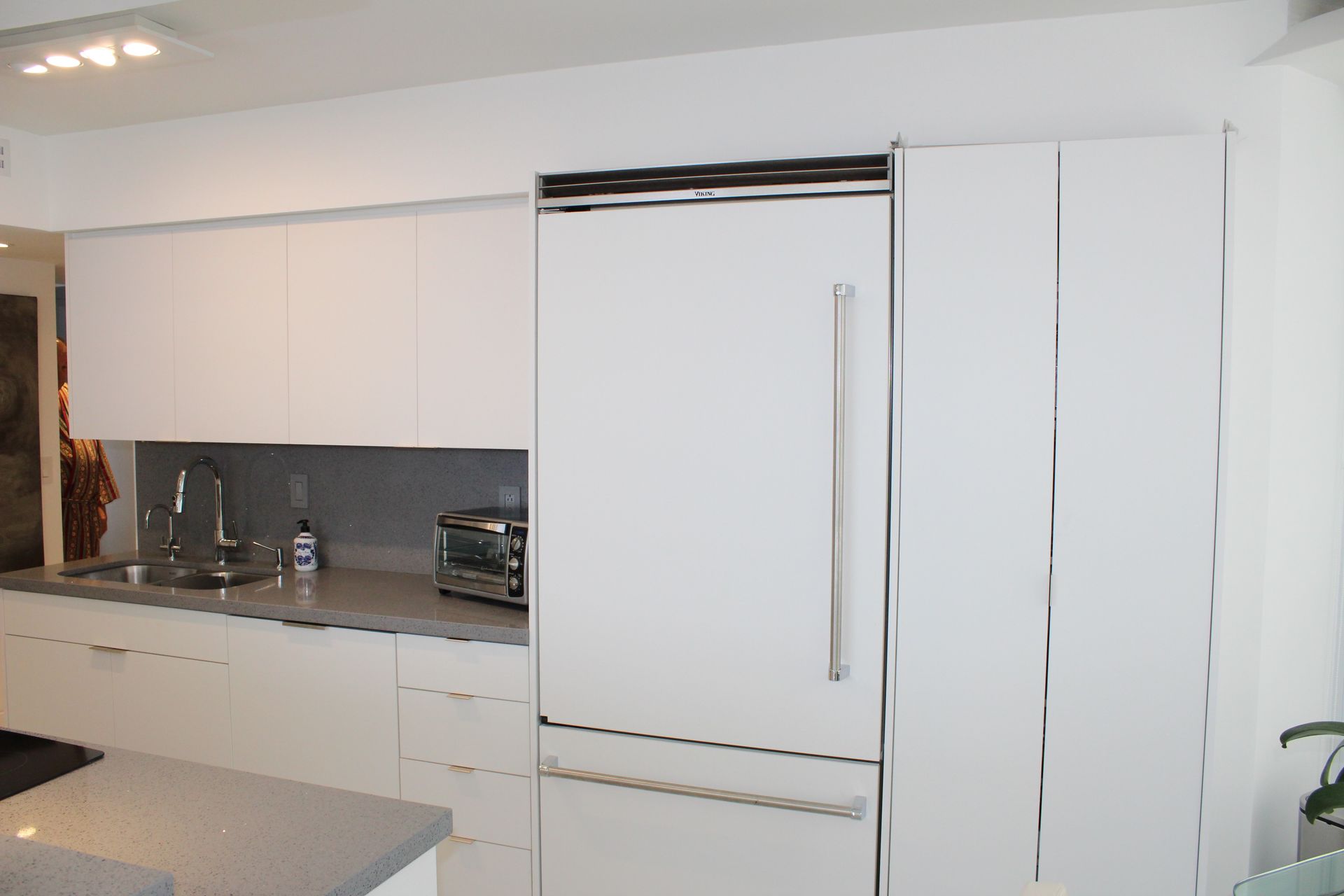 Modern kitchen cabinets finished with white cabinet doors and granite countertop with subzero fridge