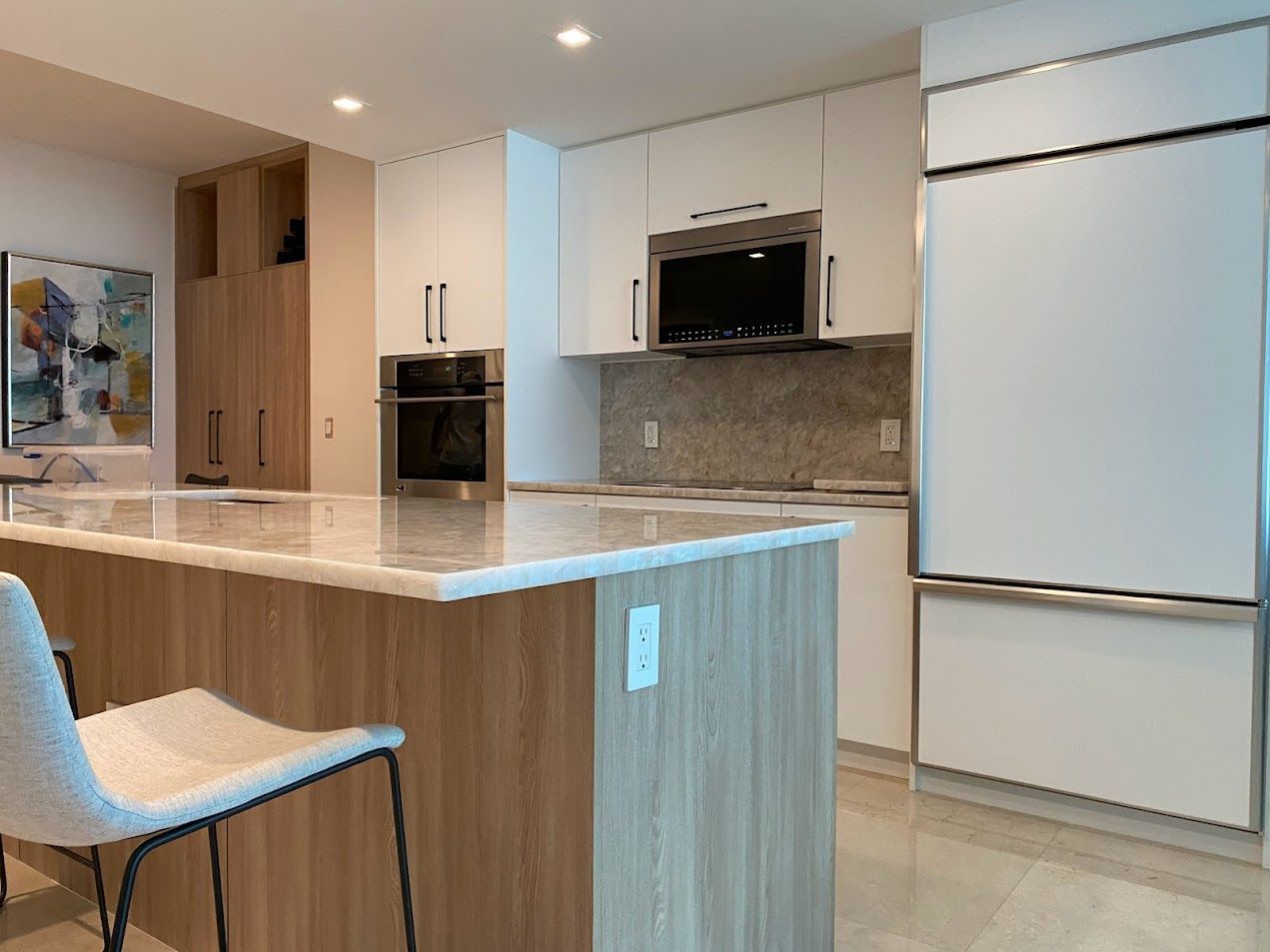 A kitchen with white cabinets , stainless steel appliances and a large island | Midtown, Miami