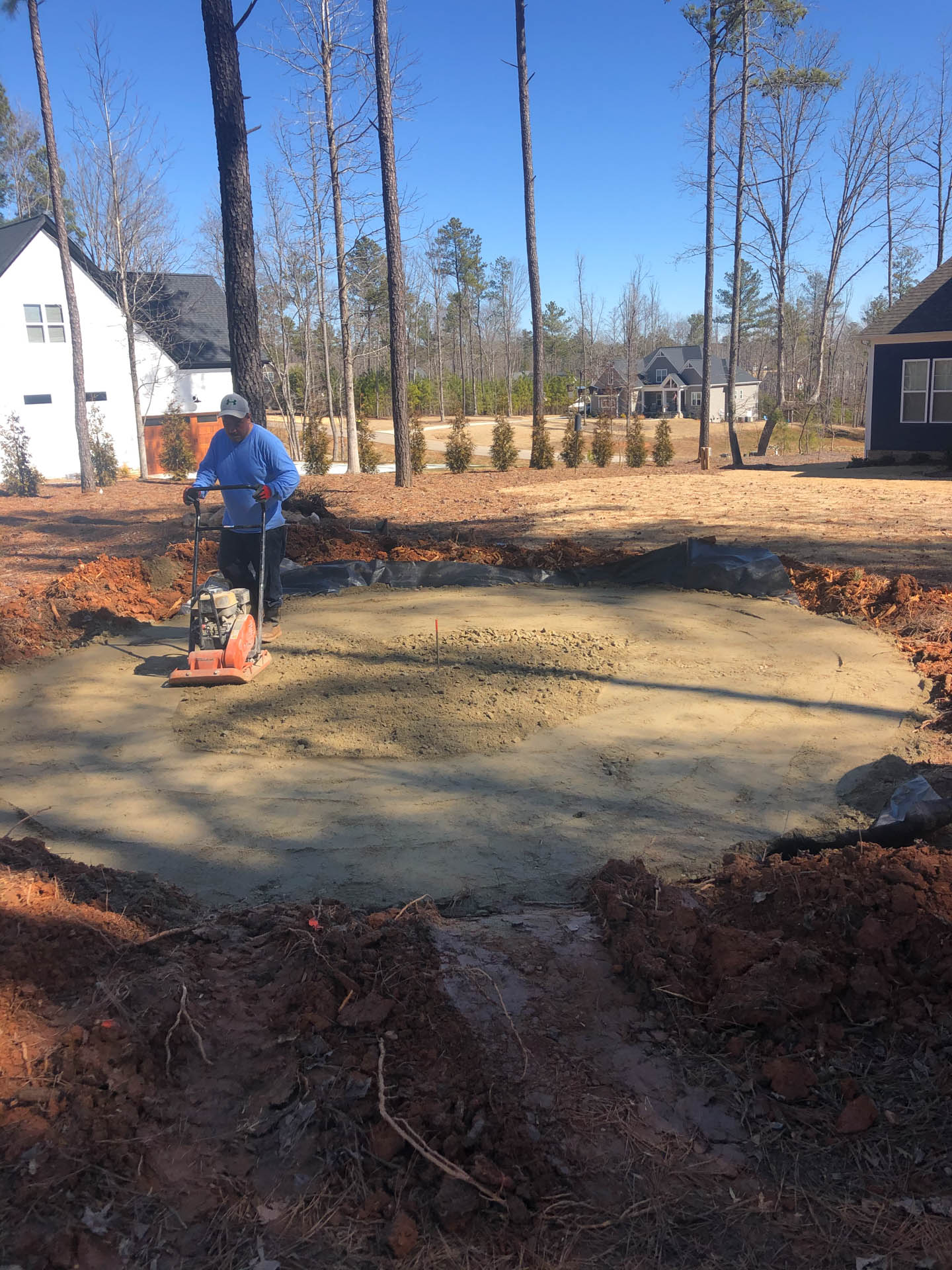 Man compacting soil with a plate compactor in a construction site.