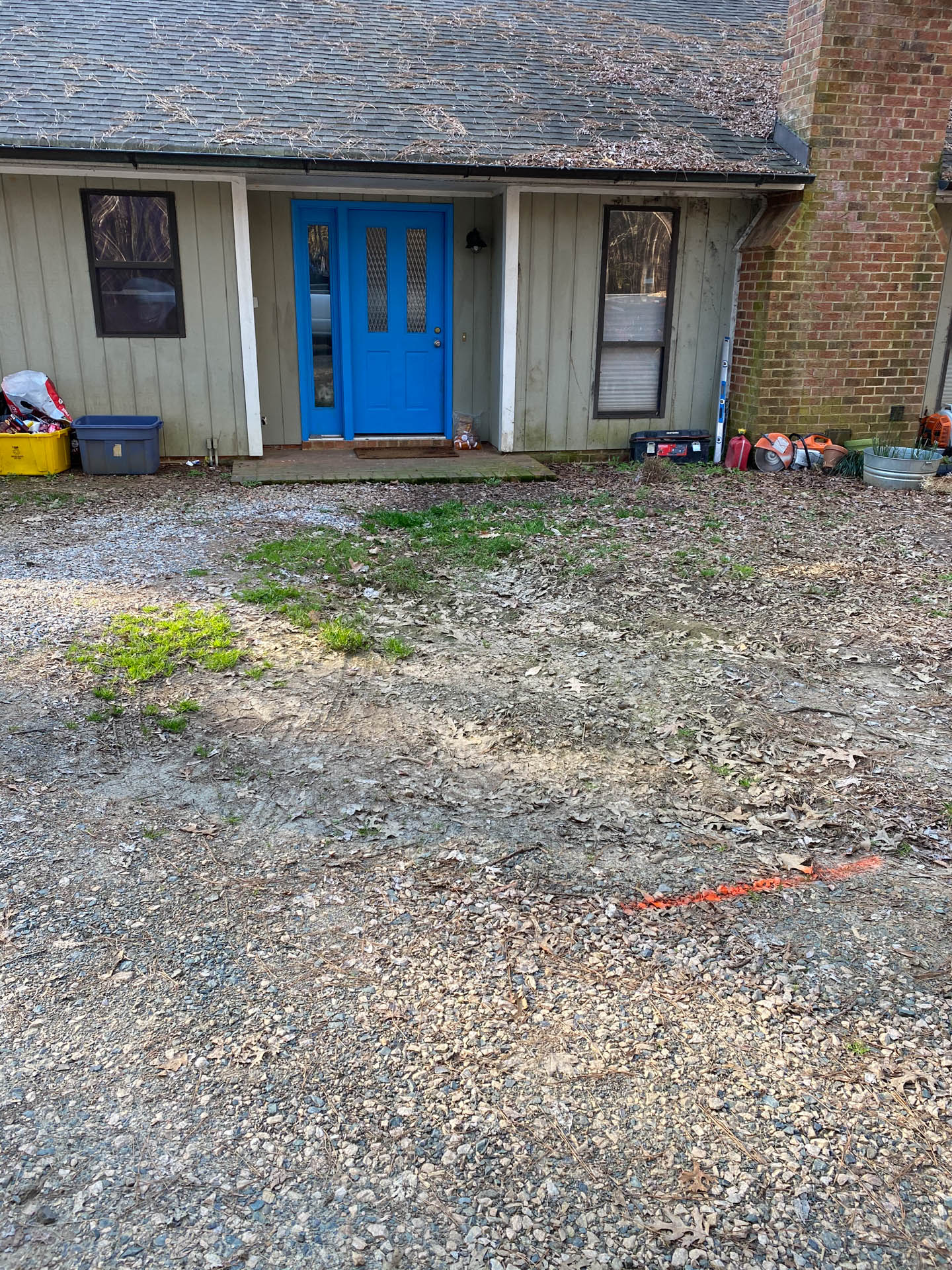 A house with a blue door and gravel driveway.