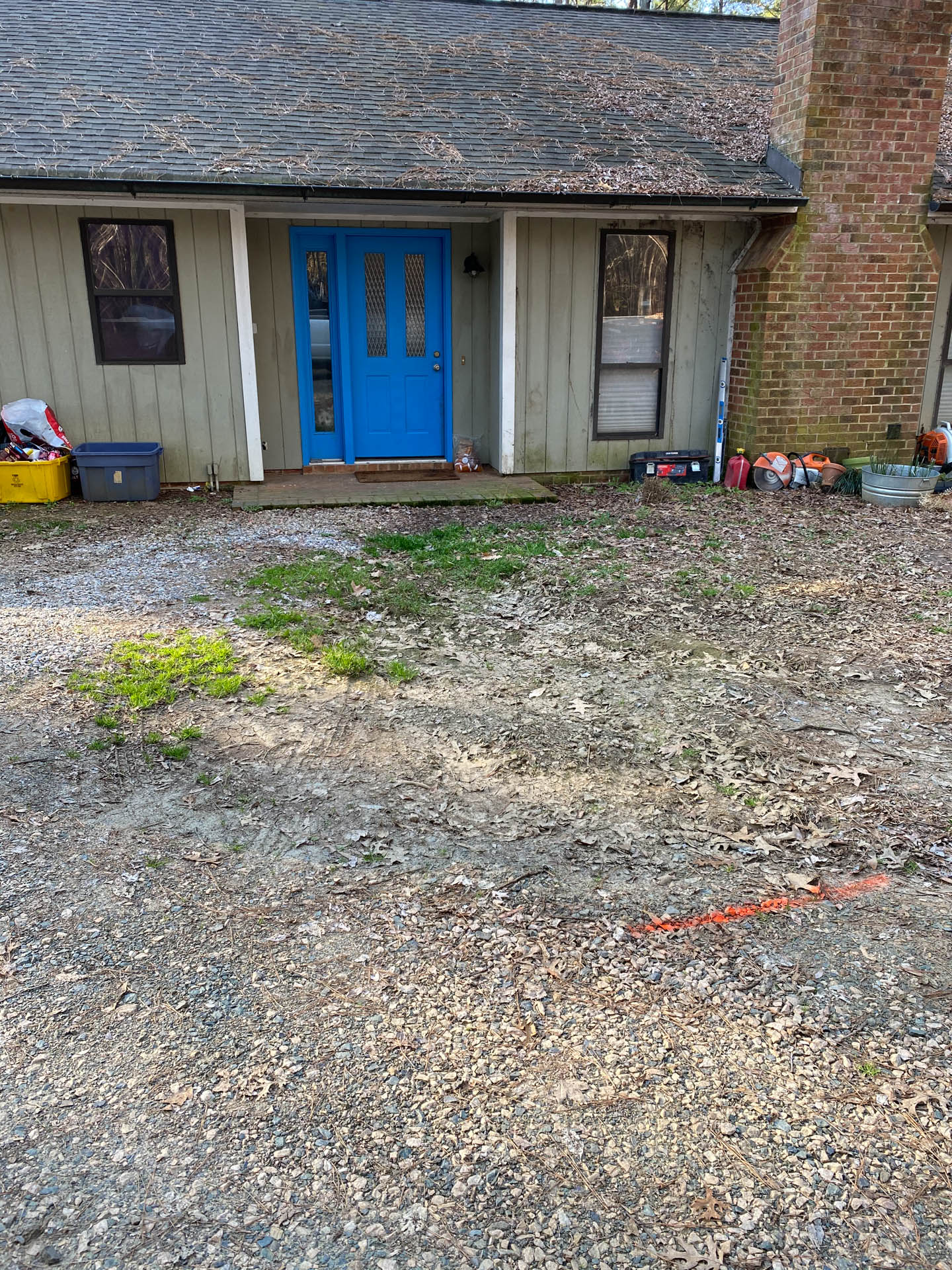 House exterior with blue front door, gravel driveway, and red brick chimney.