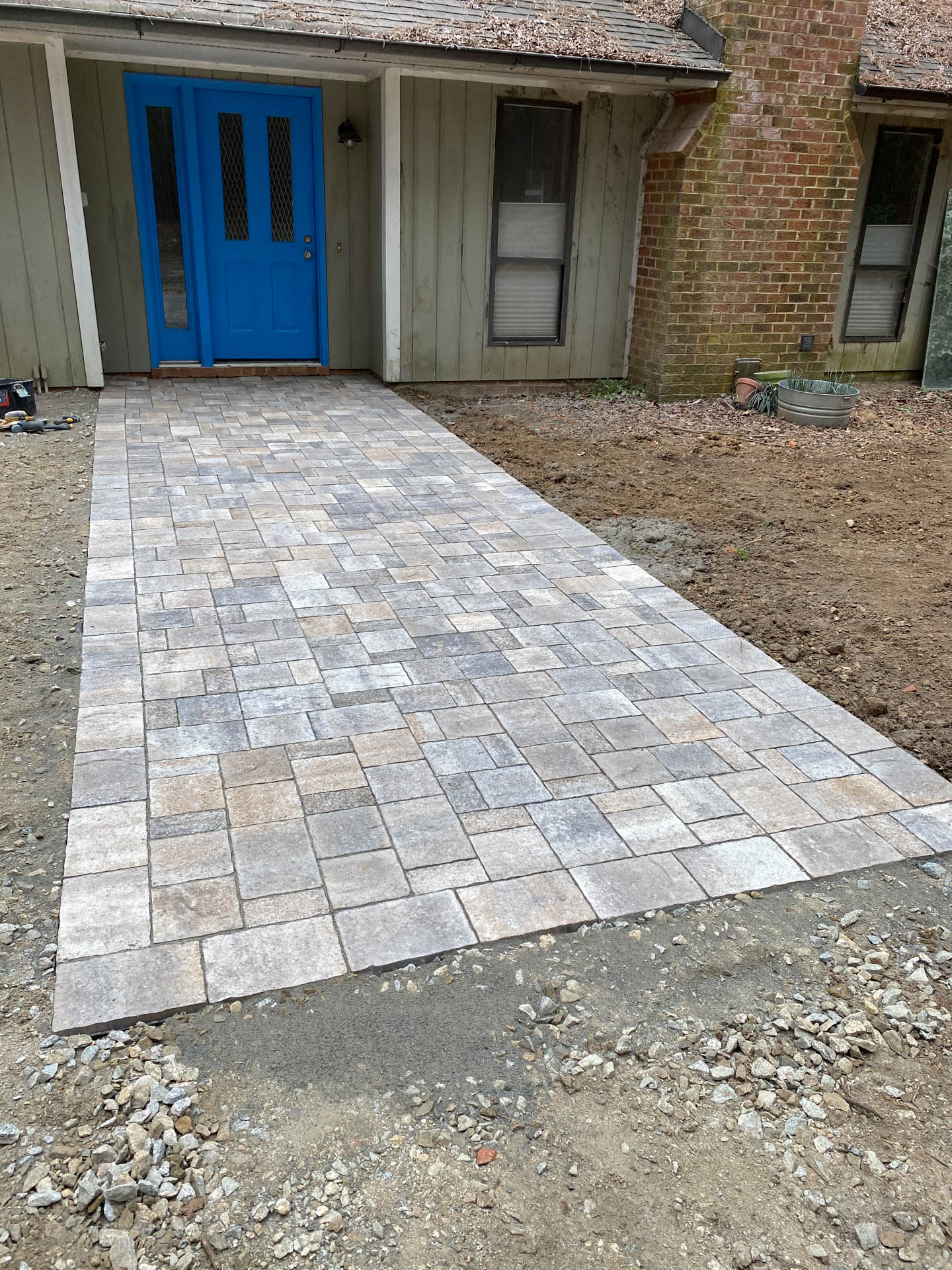 Stone paver walkway leading to a blue front door.