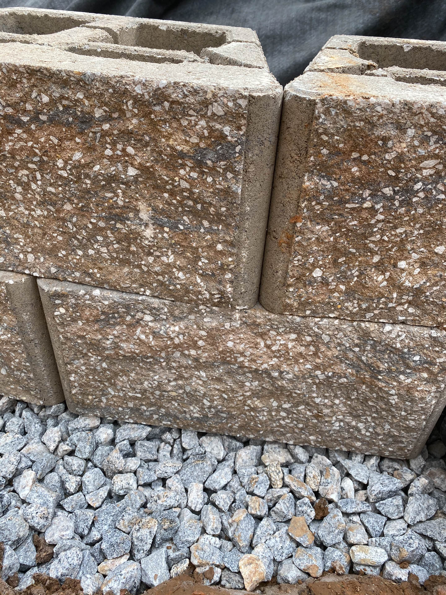 Close-up of brown and gray retaining wall blocks stacked on gravel.