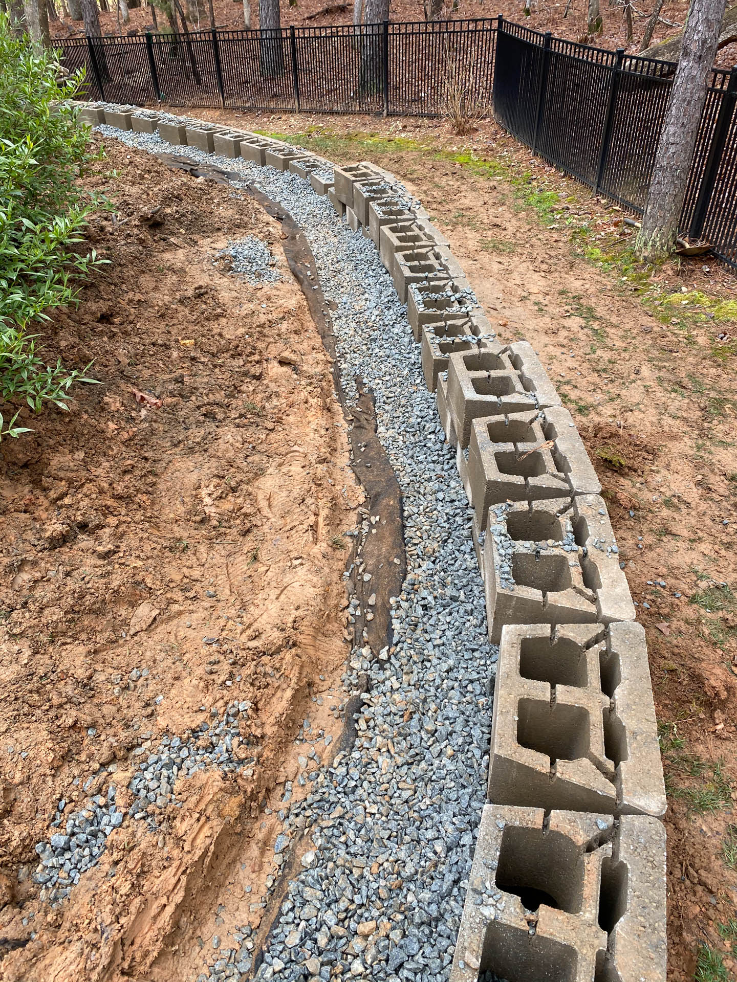 Stone blocks create a retaining wall along a curved path filled with gravel.