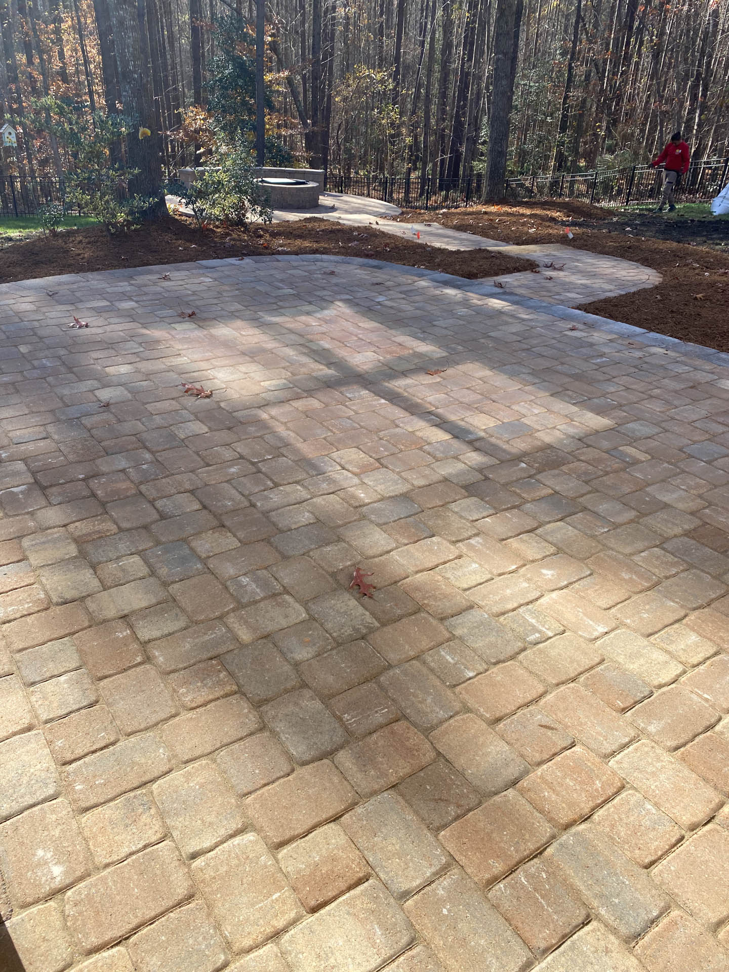 Brick paver patio with trees in background, sunny day.