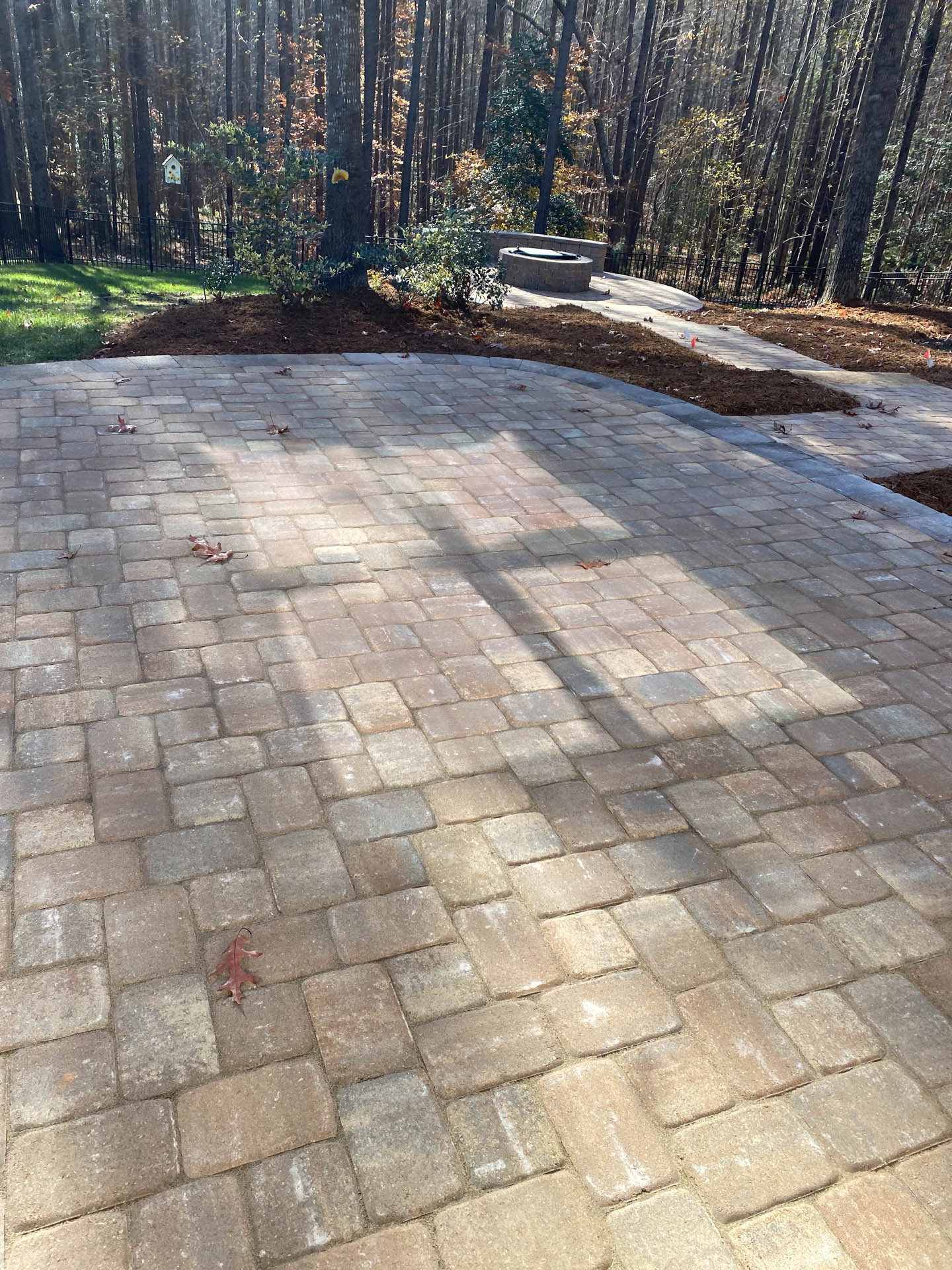Brick patio in a yard with trees in the background.