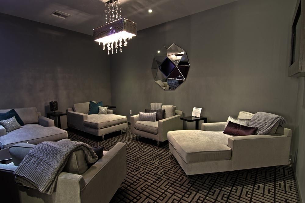 Modern gray living room with sectional sofas, chandelier, geometric wall art, and patterned carpet
