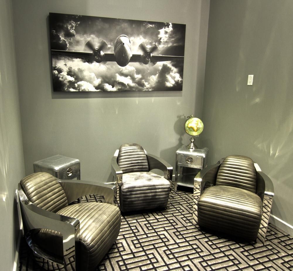 Modern lounge with black-and-gray chairs, patterned carpet, side tables, and a black-and-white wall art panel.