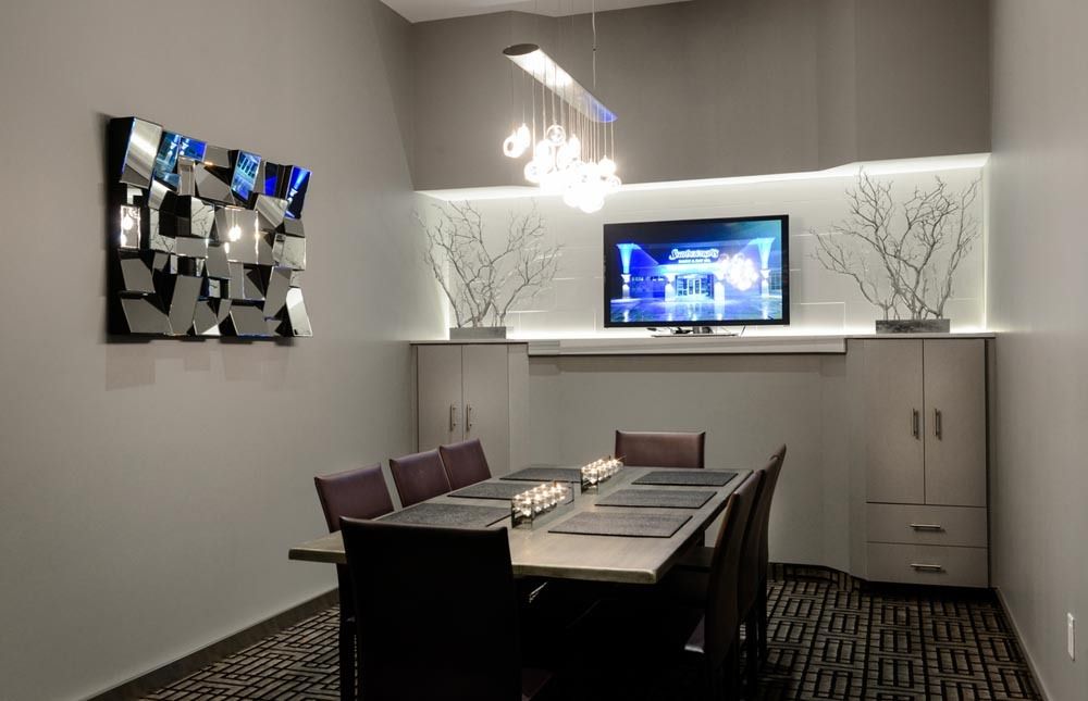 Modern dining room with a table, chairs, wall art, pendant light, and a TV in a recessed shelf