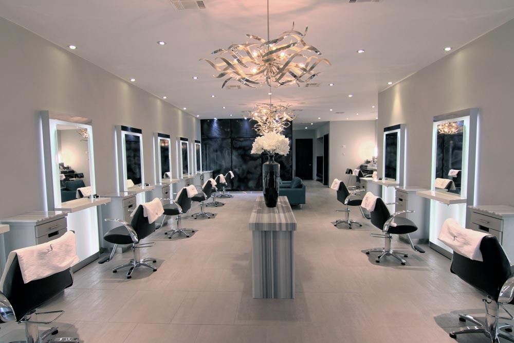 Modern hair salon with styling stations, mirrors, and a sleek chandelier