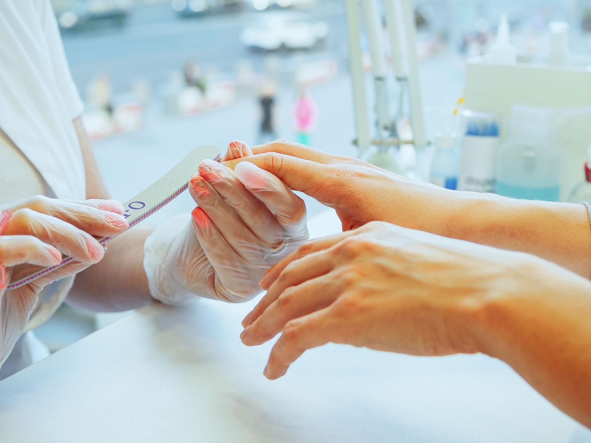 Hands receiving a manicure with white nail polish in a bright salon