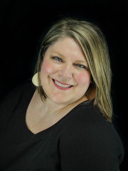 Smiling person in a black top against a dark background