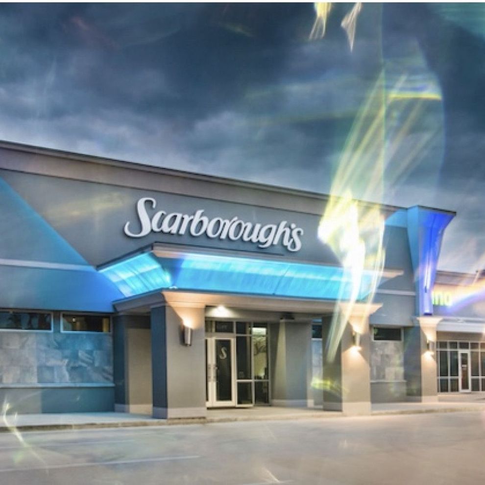 Scarboroughs storefront with blue awning and illuminated entrance at night
