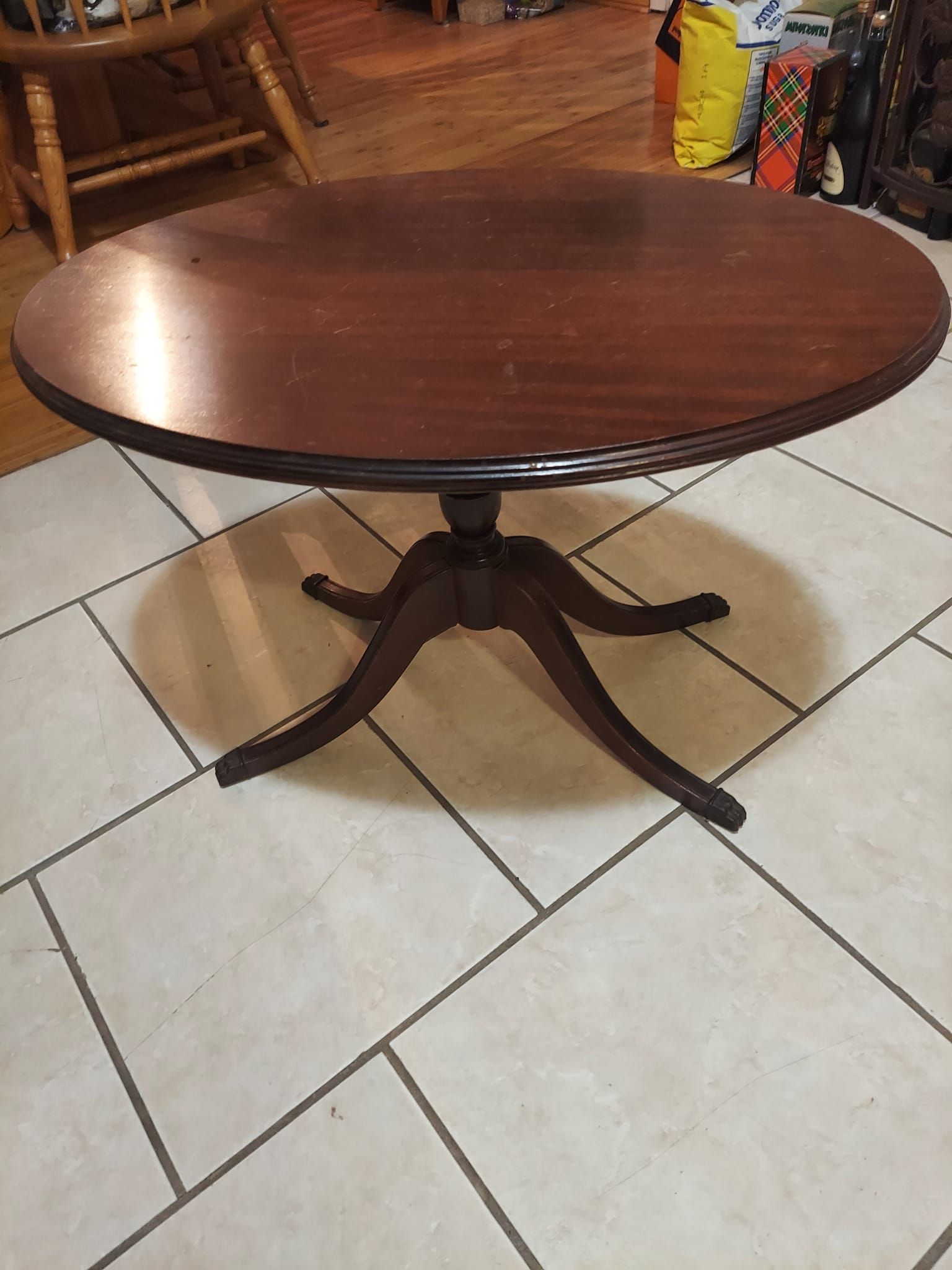 A round wooden table is sitting on a tiled floor