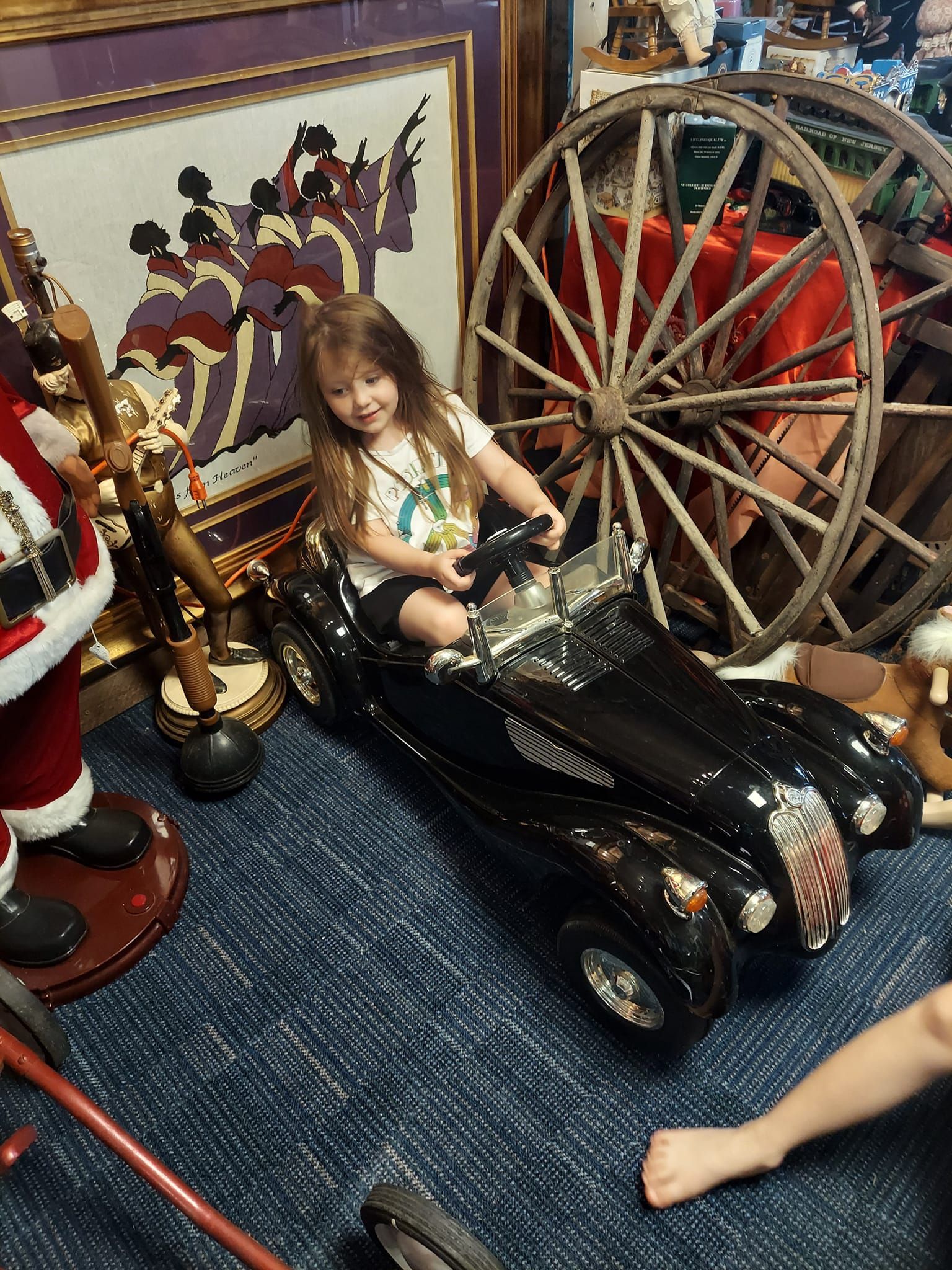 A little girl is sitting in a black toy car