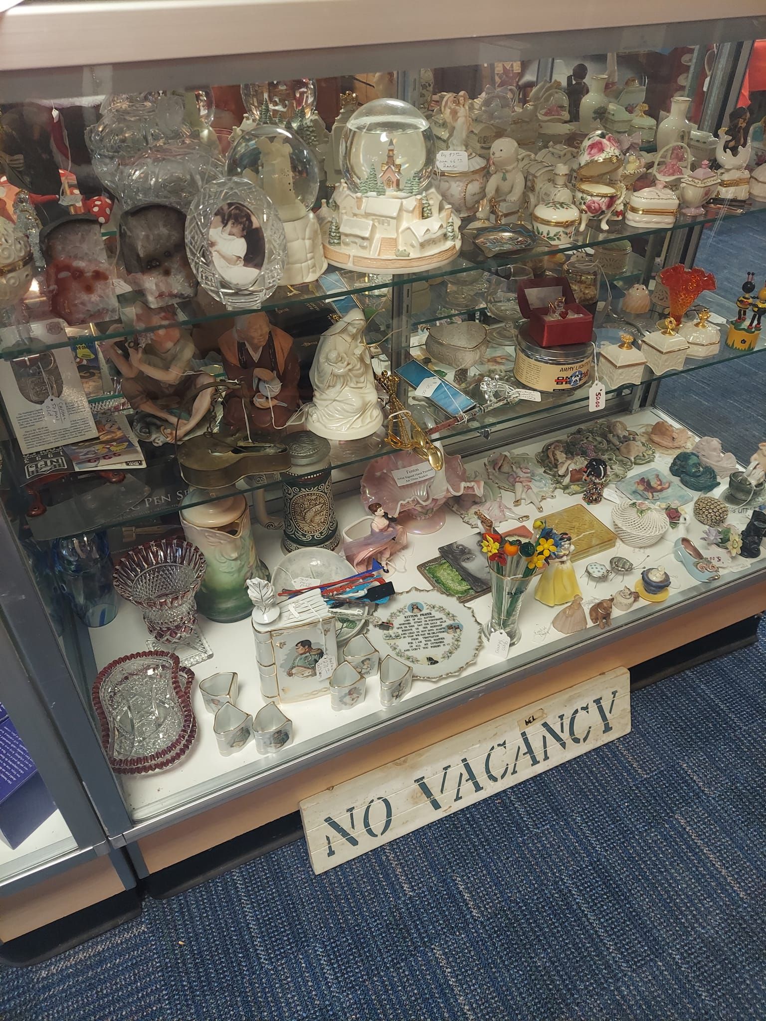 A glass display case filled with lots of items and a sign that says `` no vacancy ''.
