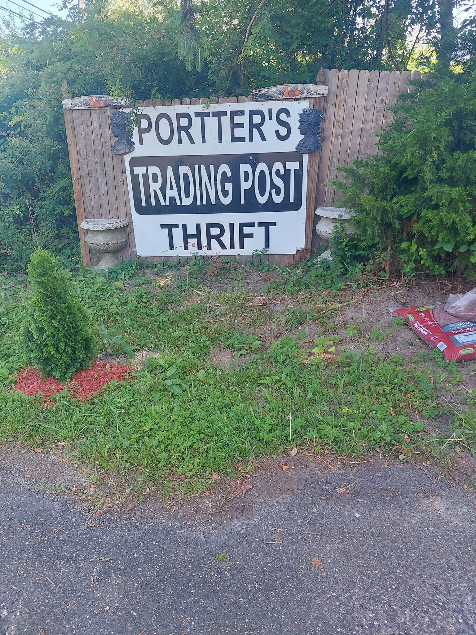 A sign for porter 's trading post thrift is sitting in the grass.