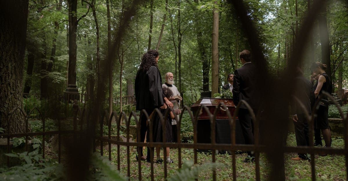 A group of people are standing around a coffin in a cemetery.