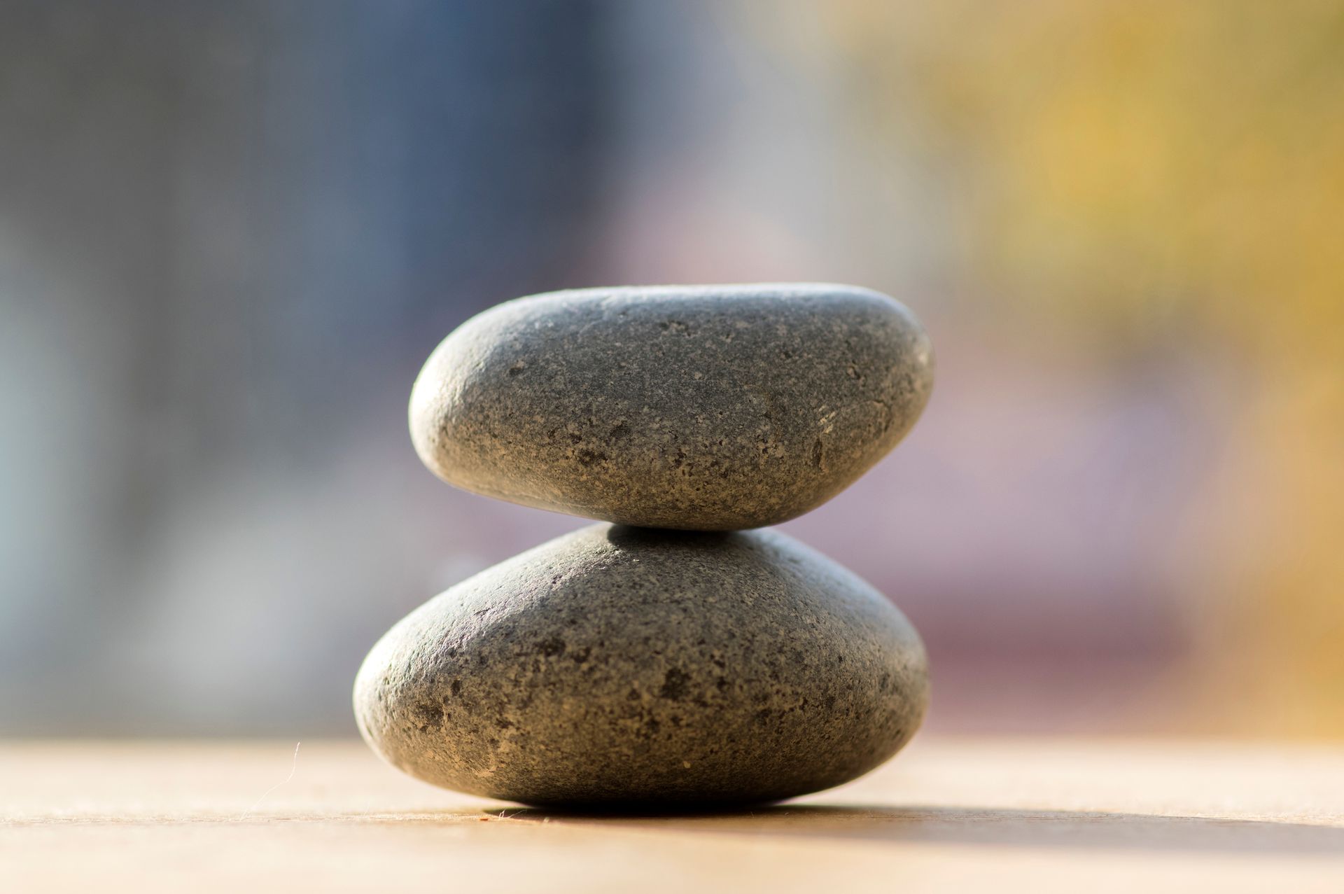 Two stacked smooth pebbles on a soft blurred background, with warm light