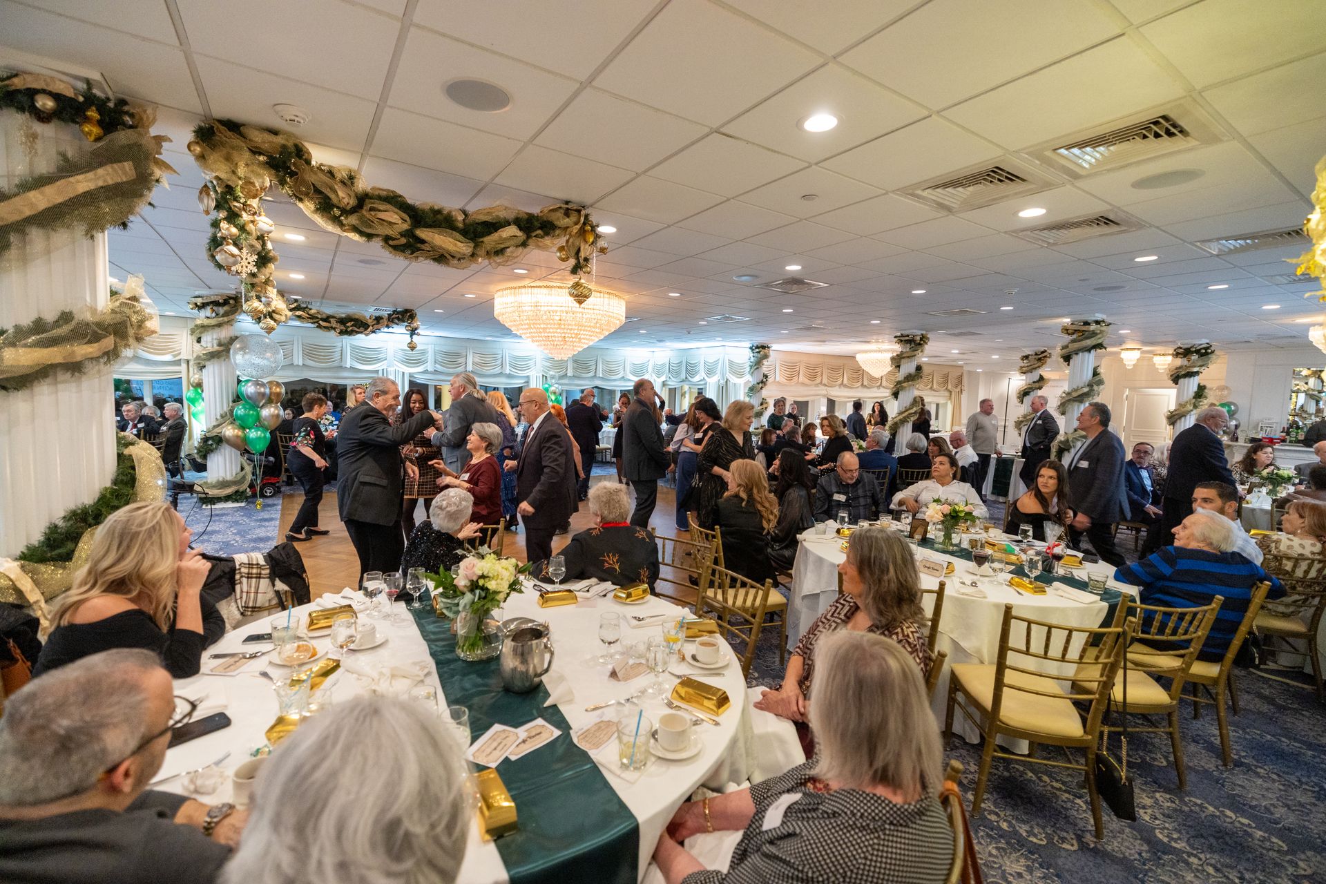 People at a festive event, seated at round tables with decorations, indoors.