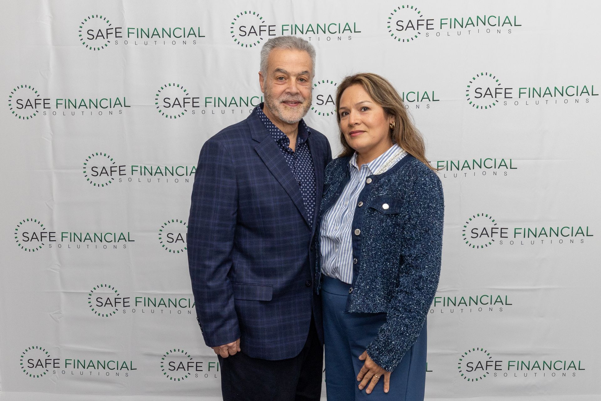 Man and woman posing in front of a backdrop with 