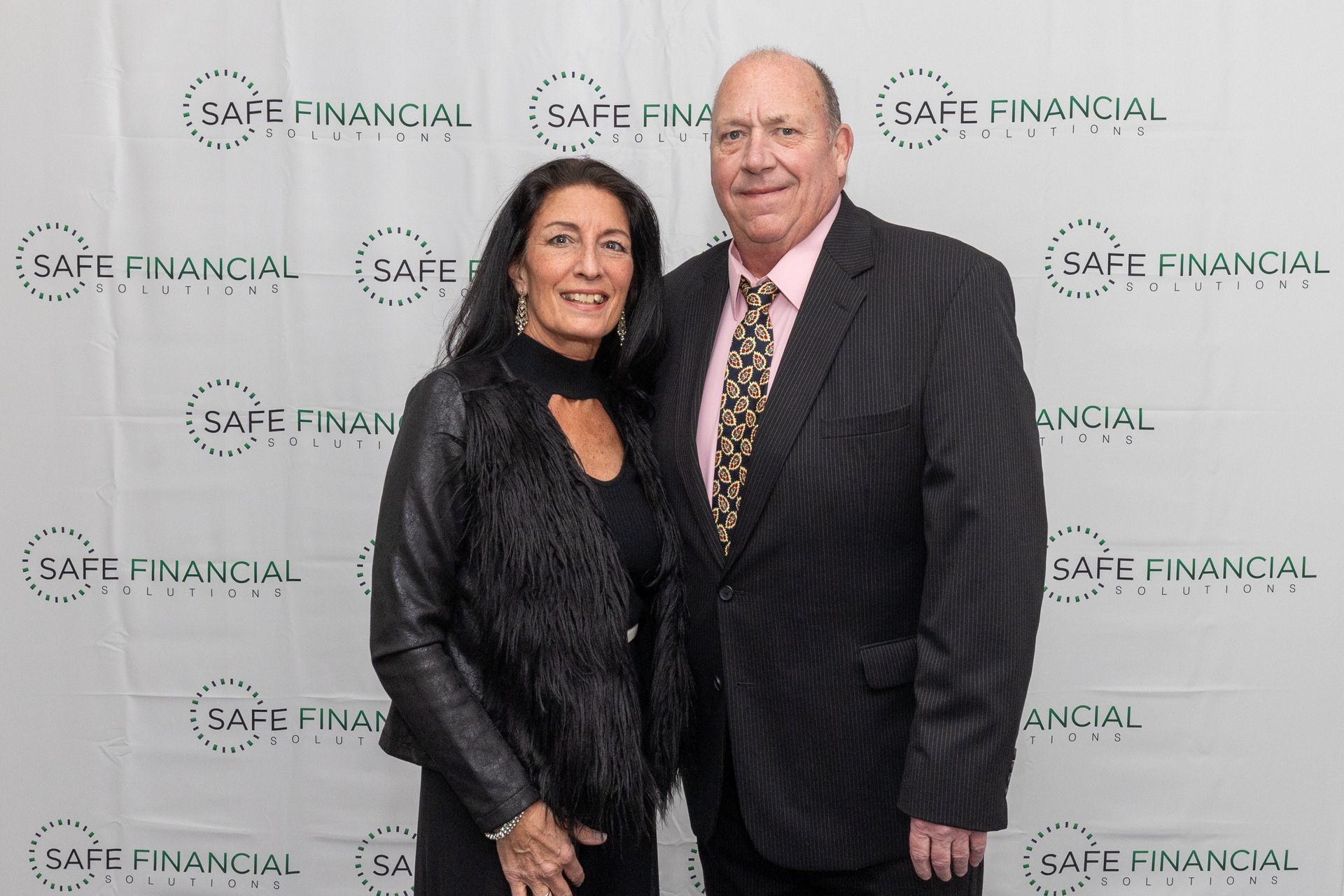 A couple posing in front of a backdrop with the 