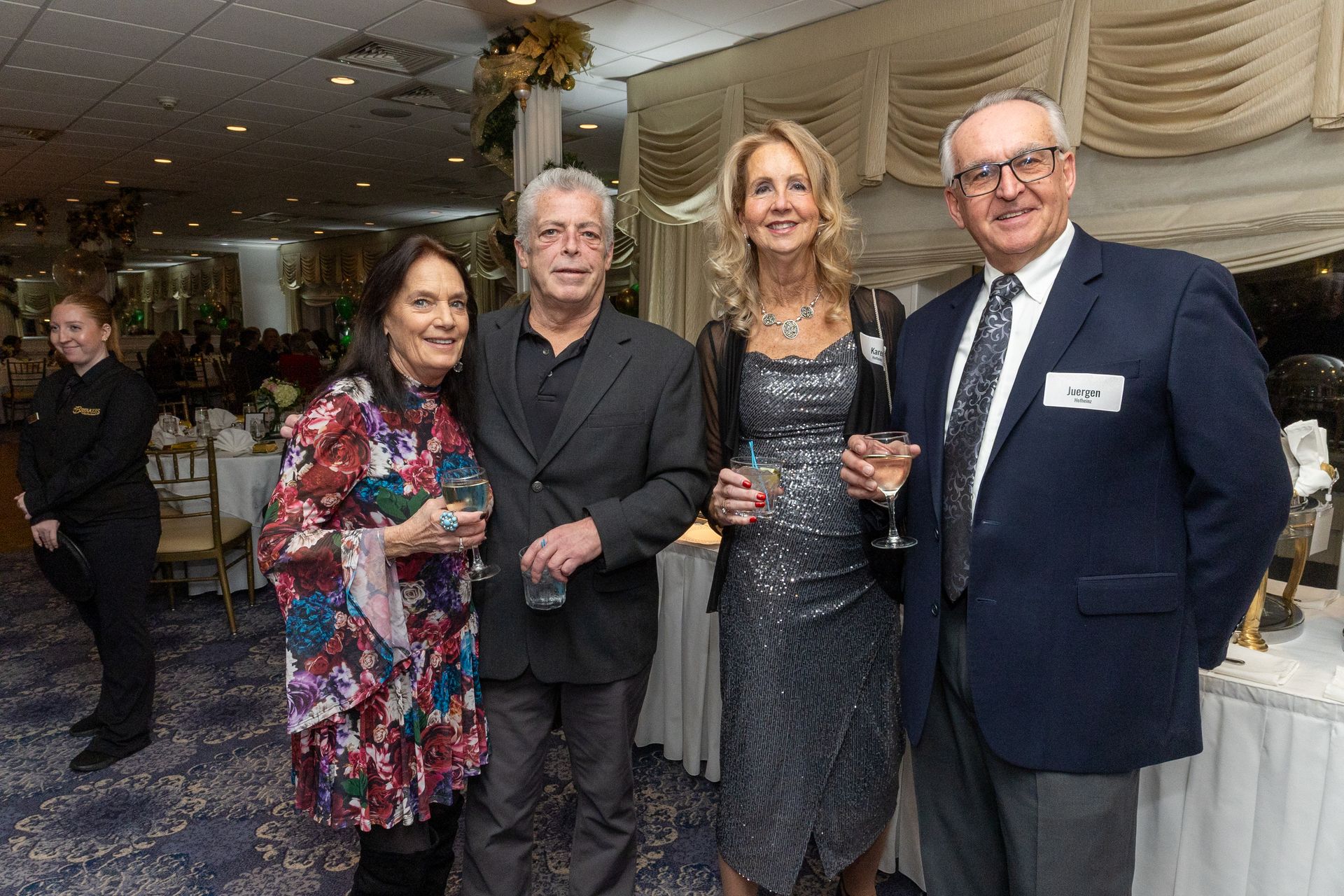 Four people in formal attire at an event, posing and smiling indoors.