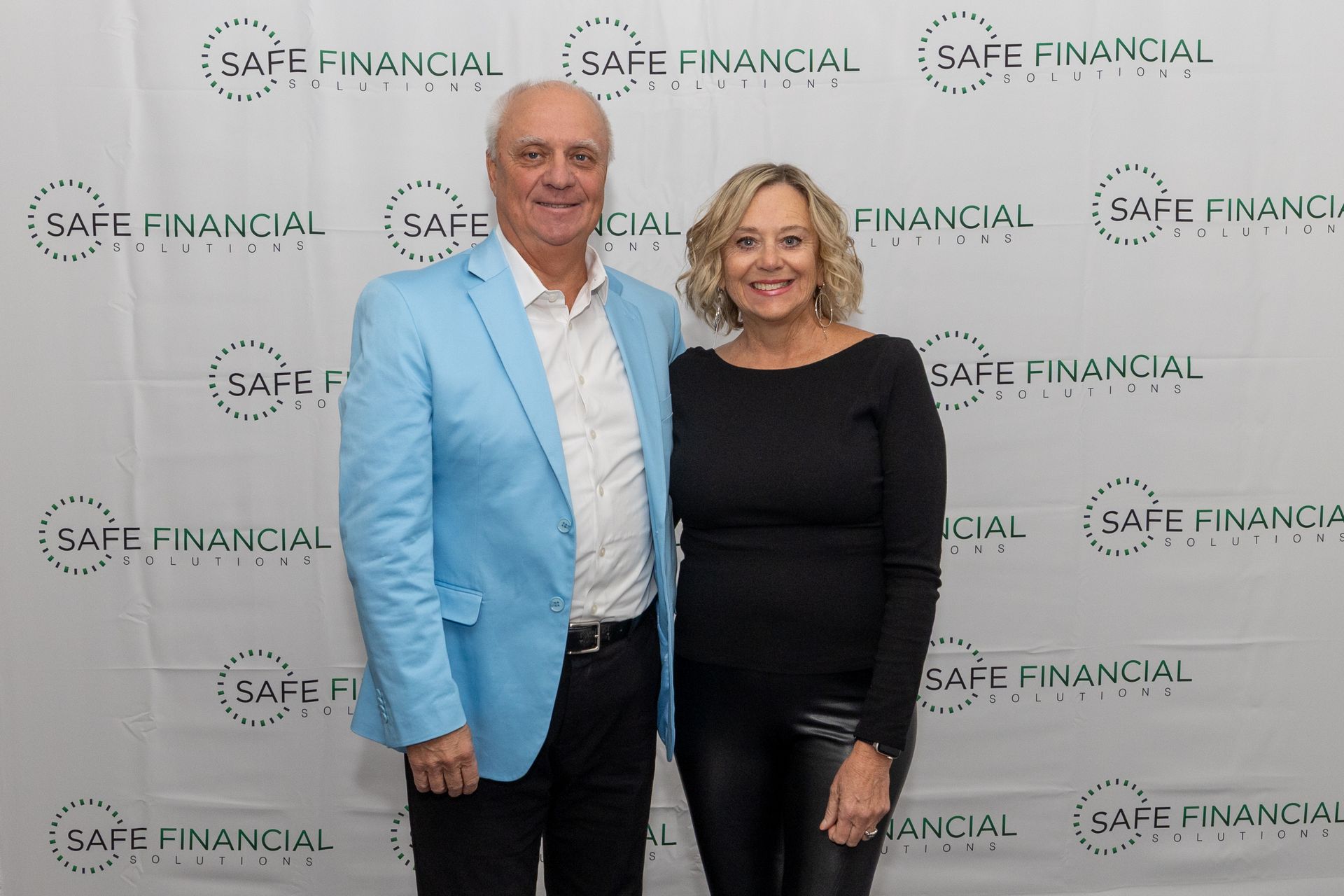 Man and woman posing in front of a backdrop with 