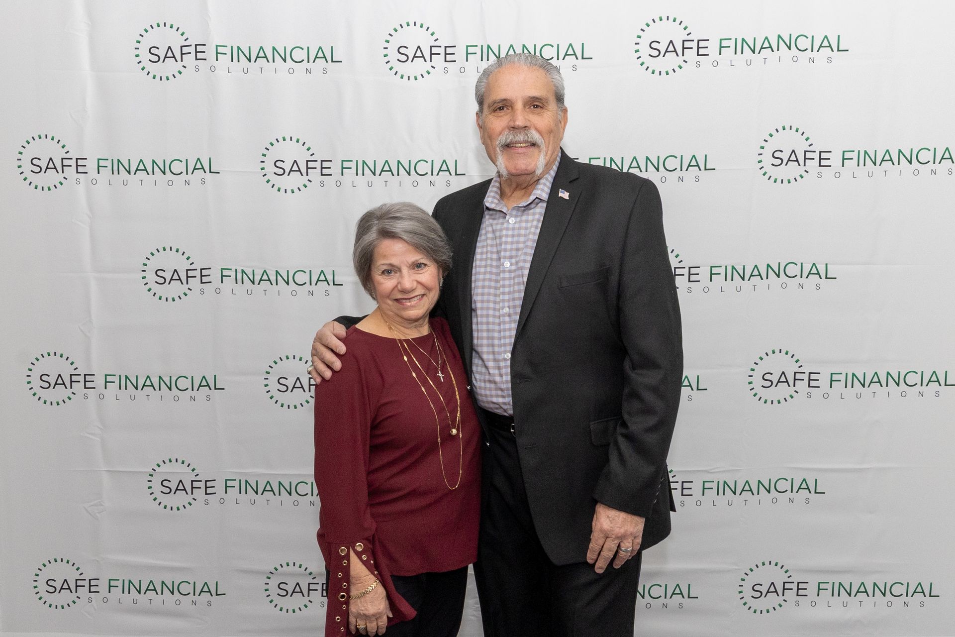 Couple poses in front of a backdrop with 