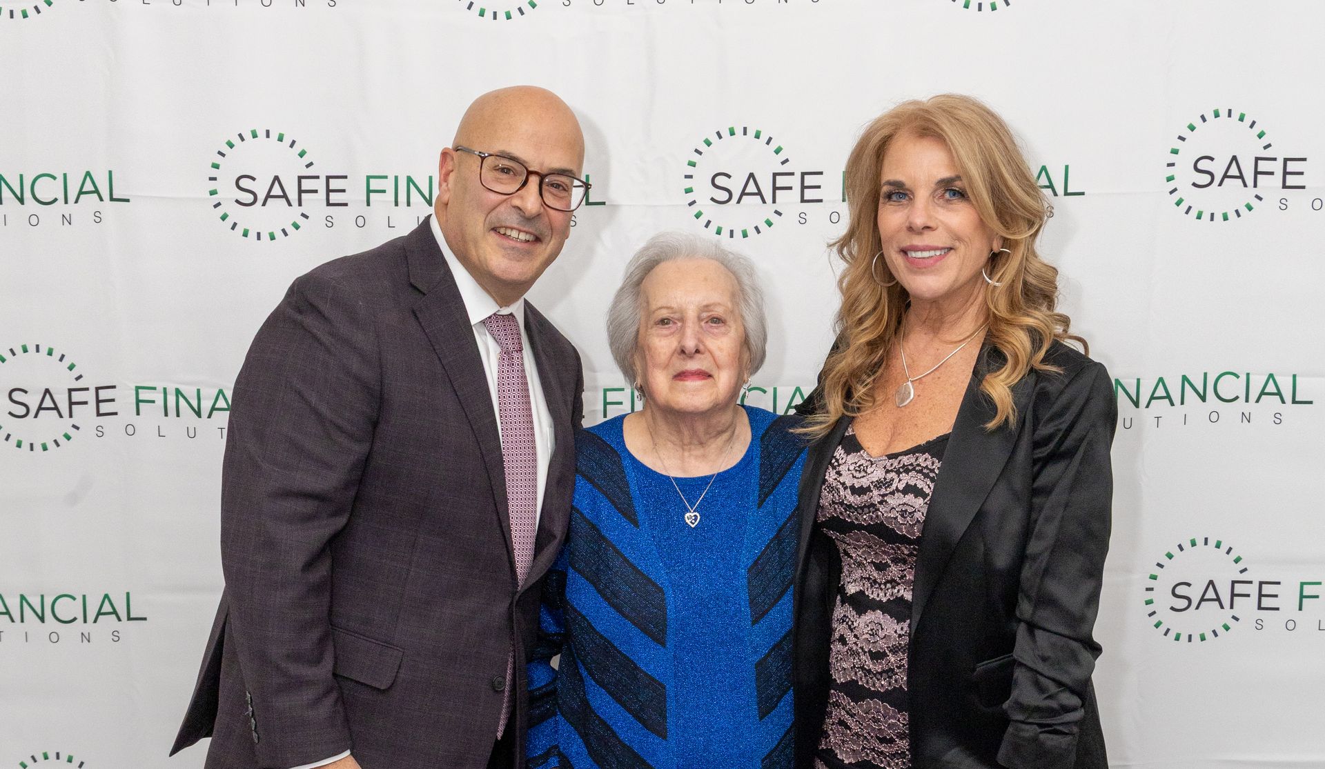 A man in a suit, a woman in a sparkly blue dress, and a woman in a black jacket.