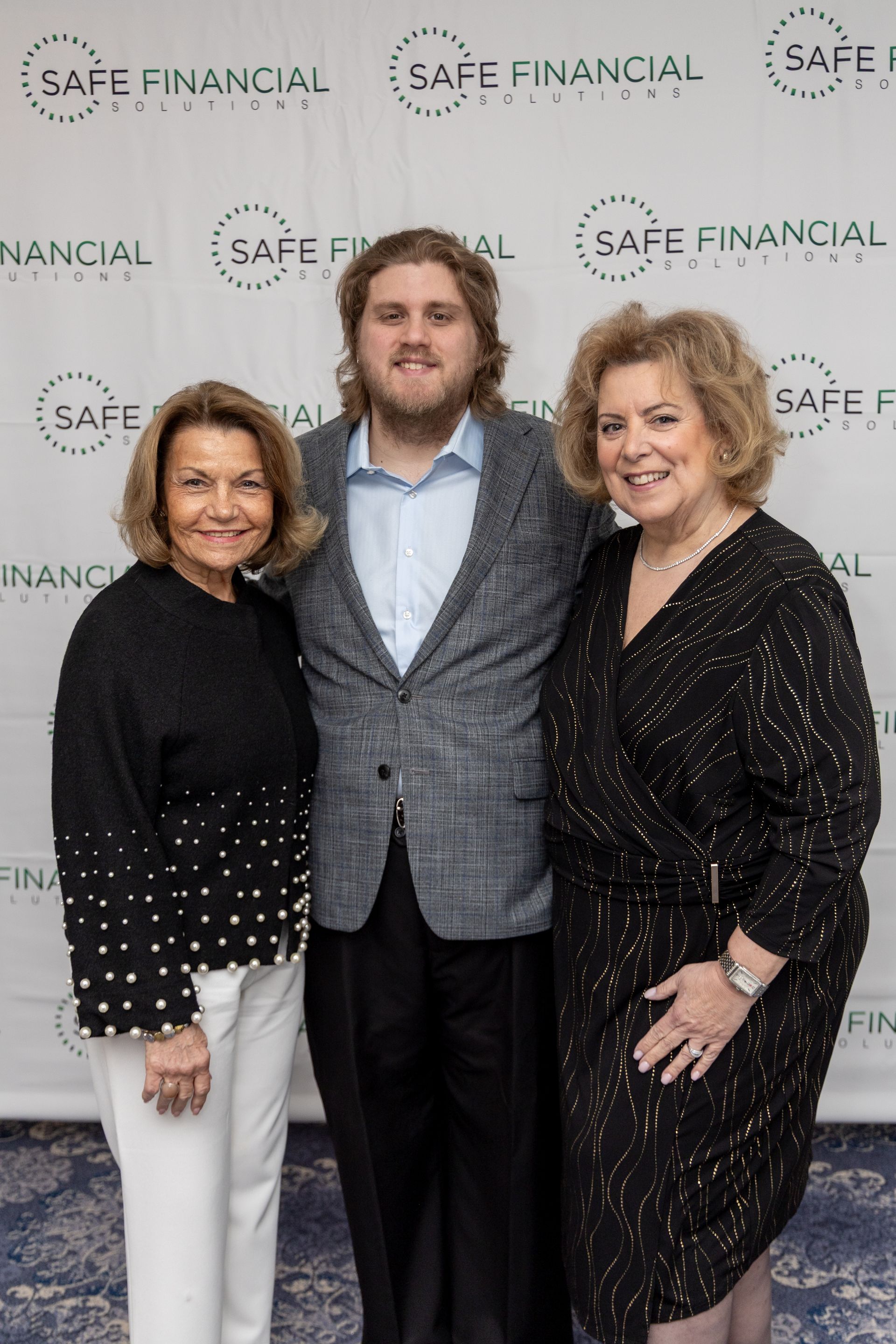 Three people pose in front of a backdrop with 