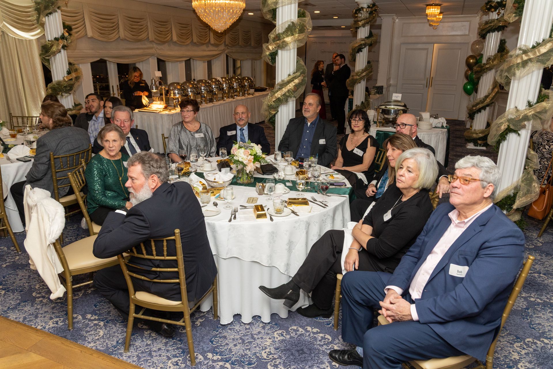 People seated at round tables in a decorated dining room, attending an event.