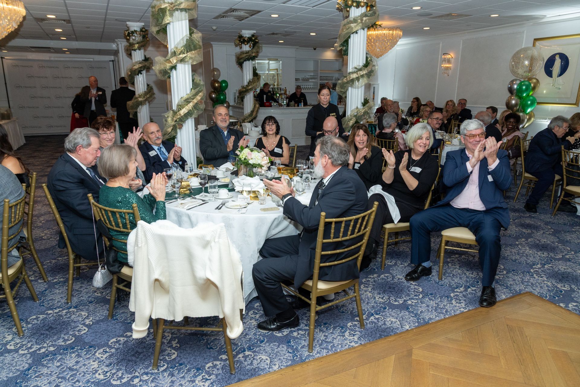 People at tables clapping in a decorated banquet hall.