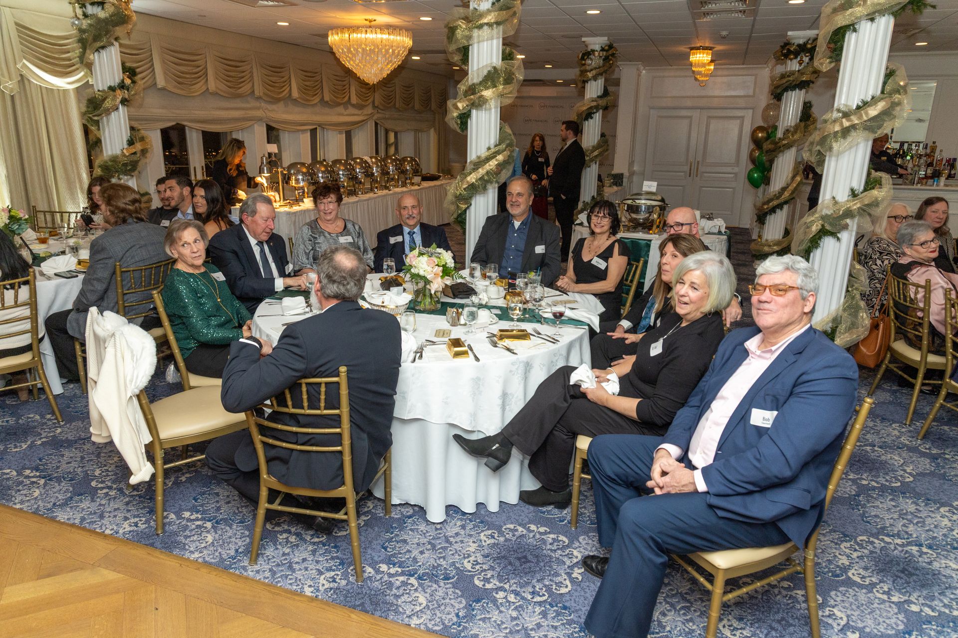 People seated at round tables in a decorated banquet hall, some looking towards the camera.