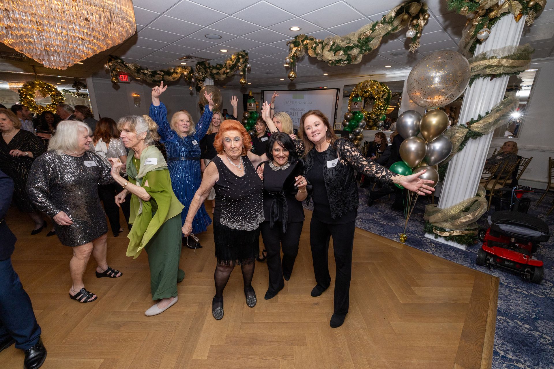 People dancing at a party in a decorated room with gold and silver accents.