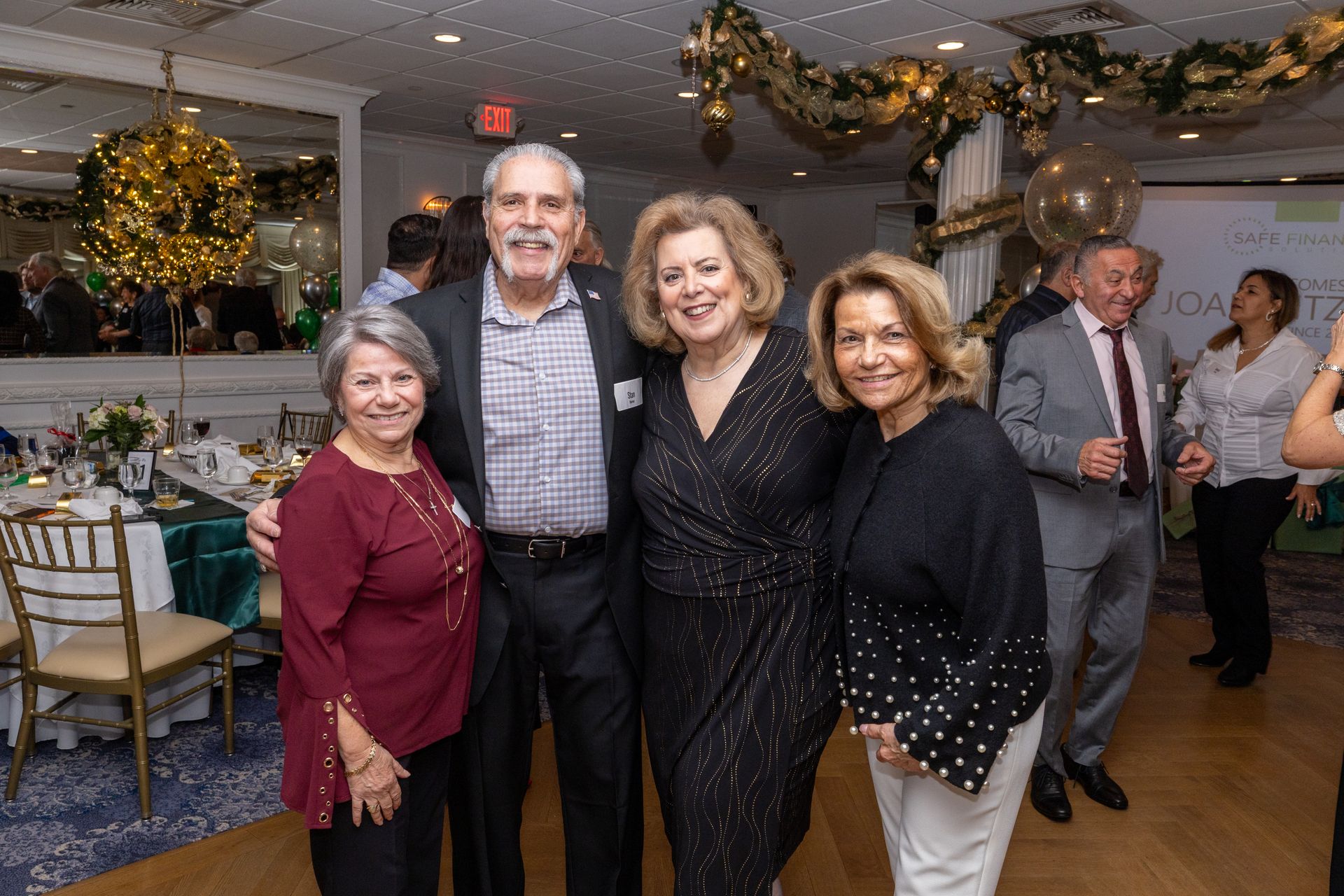 Group of people smiling at an event with gold and green decorations.