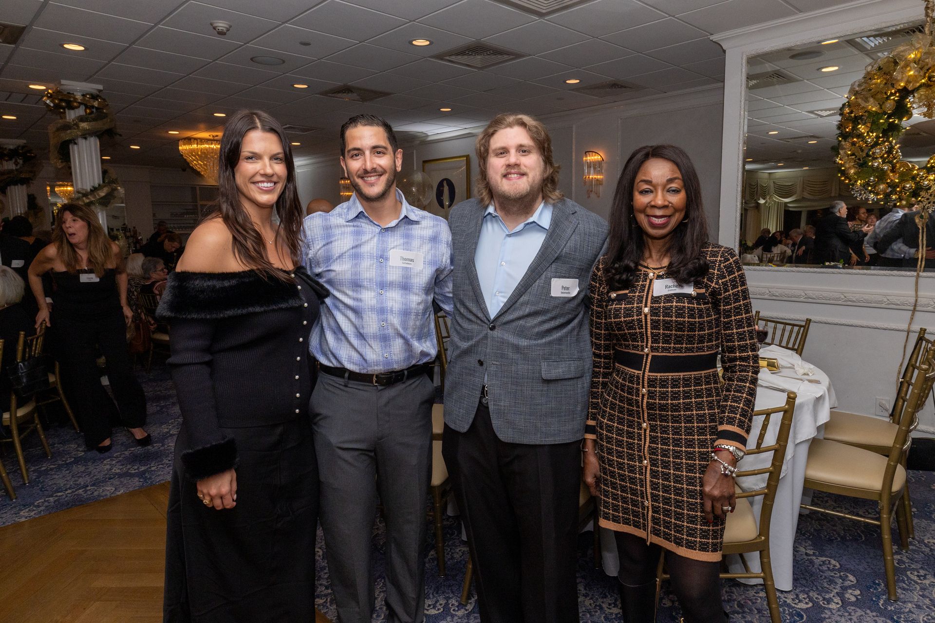 Four people smiling, posing for a photo at an event, inside a room.