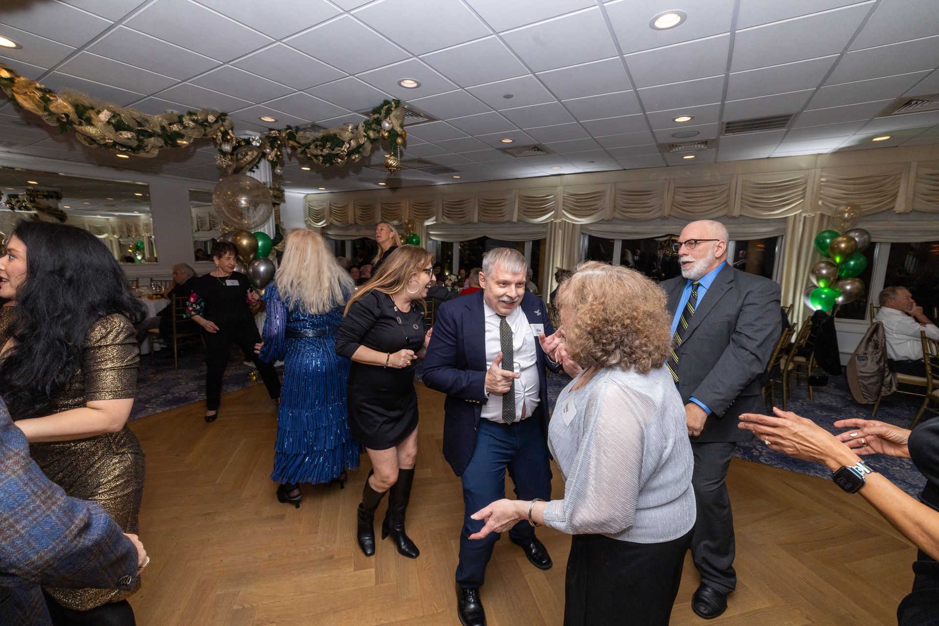 People dancing at a party in a room decorated with gold and green accents.