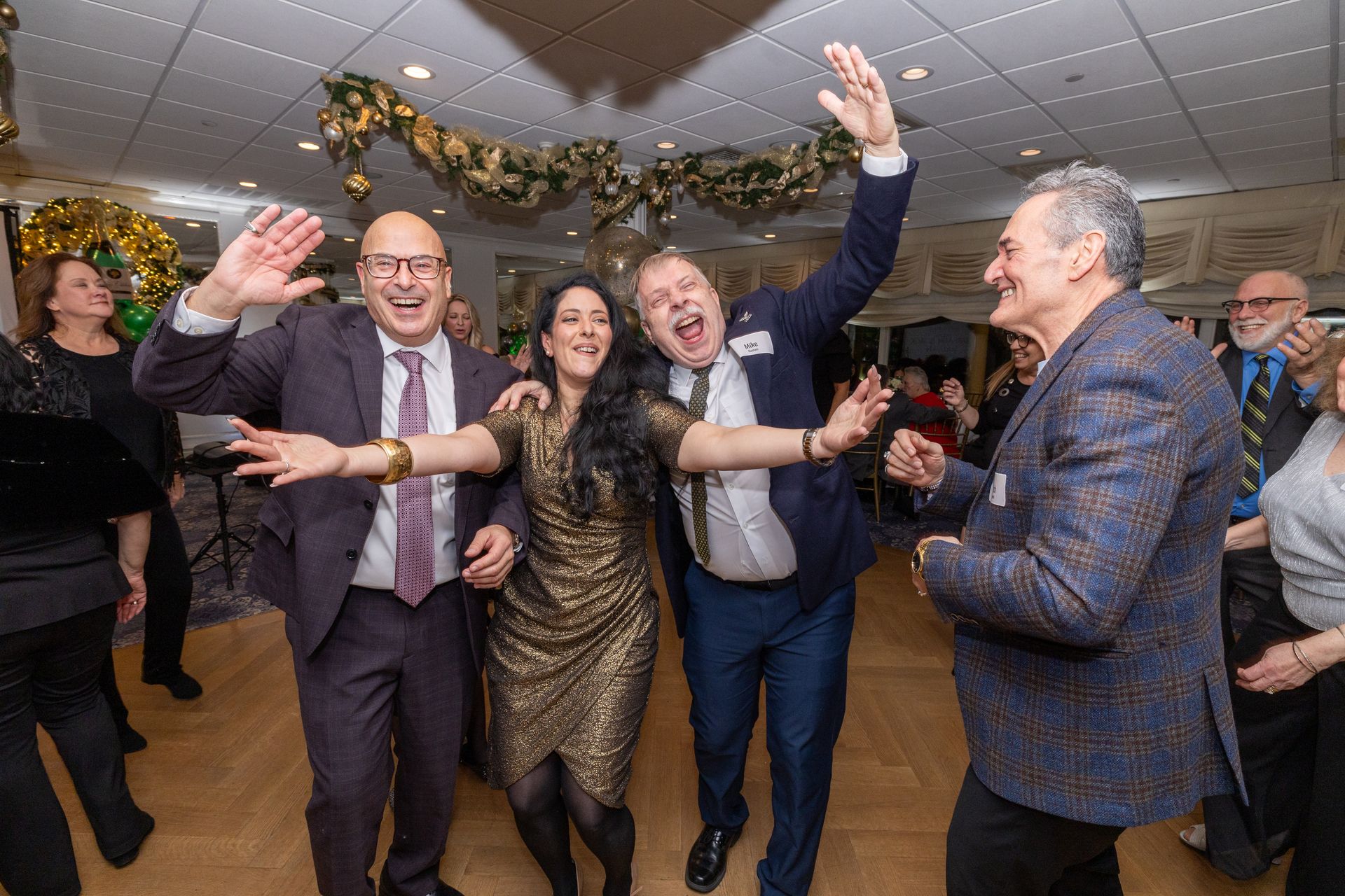People dancing joyfully at a party, raising arms in a decorated room.